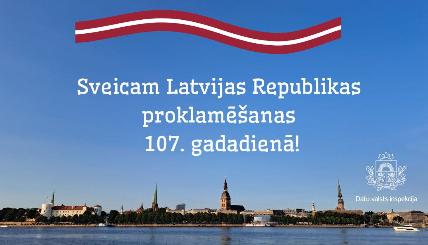 Panorāmas foto ar Rīgas pilsētas skatu saulainā dienā, priekšplānā Daugava. Attēla augšdaļā redzama stilizēta Latvijas karoga lente, bet centrā — uzraksts