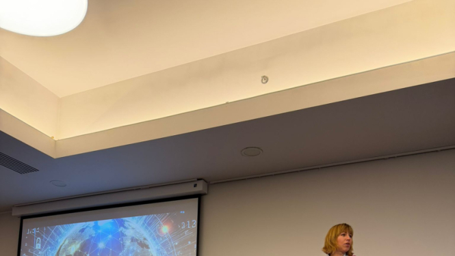 Datu valsts inspekcijas direktore uzstājas Latvijas Iekšējo auditoru institūta konferencē ar prezentāciju “Ilgtspējīga un jēgpilna personas datu aizsardzības sistēma”. Fonā redzams prezentācijas slaids ar globusa un datu tīkla vizualizāciju.